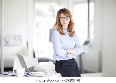 Portrait of successful middle aged businesswoman standing at her office. - Shutterstock ID 437205478
