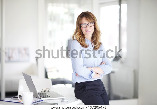 Portrait of successful middle aged businesswoman\
standing at her\
office.