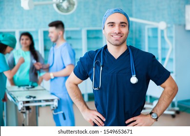 Portrait Of A Successful Professional Doctor. Staff Medical Faculty. Multinational People - Doctor, Nurse And Surgeon. A Group Graduates A Medical University In A Surgical Room. Students In Scrubs.