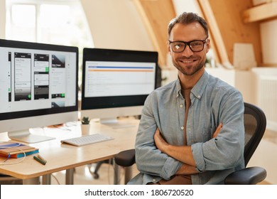 Portrait of successful software developer in eyeglasses standing with arms crossed and smiling at camera at office - Shutterstock ID 1806720520