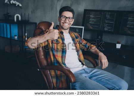 Portrait of successful trader guy sit chair demonstrate thumb up approval workplace desktop business center indoors