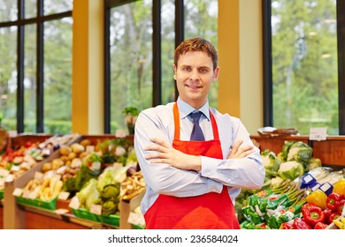 Portrait Of Supermarket Store Manager In Front Of Fresh Vegetables