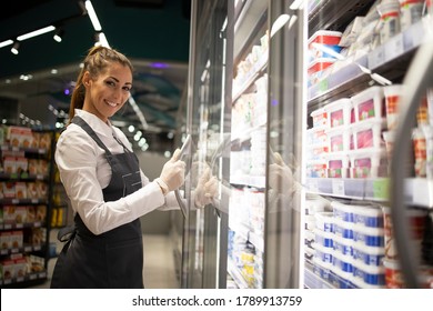 Portrait Of Supermarket Worker Opening The Freezer With Food. Grocery Store Job Position.