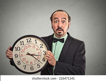 Portrait Surprised Business Man In Suit Holding Wall Clock Isolated Grey Wall Background. Race Against Time, Time Goes By, Running Out Of Time, No Time For Work, Time Running, Time Is Money Concept 