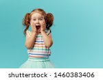 Portrait of surprised cute little toddler girl child standing isolated over blue background. Looking at camera. hands near open mouth