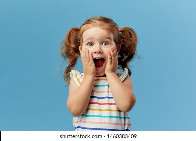 Portrait of surprised cute little toddler girl child standing isolated over blue background. Looking at camera. hands near open mouth - Shutterstock ID 1460383409