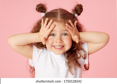 Portrait of surprised cute little toddler girl child over pink background. Looking at camera. Points hands to the left side. Advertising childrens products - Shutterstock ID 1750128242