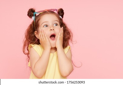 Portrait of surprised cute little toddler girl  in sunglasses over pink background.  Child model have fun and jump. Advertising childrens products