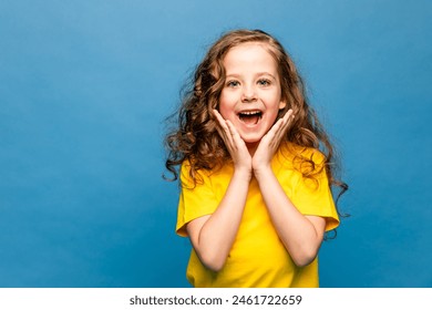 Portrait of surprised cute little toddler girl child standing isolated over blue background. Looking at camera. hands near open mouth - Powered by Shutterstock