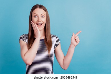 Portrait of surprised excited omg girl direct finger empty space palm cheek on blue background - Shutterstock ID 2035493549