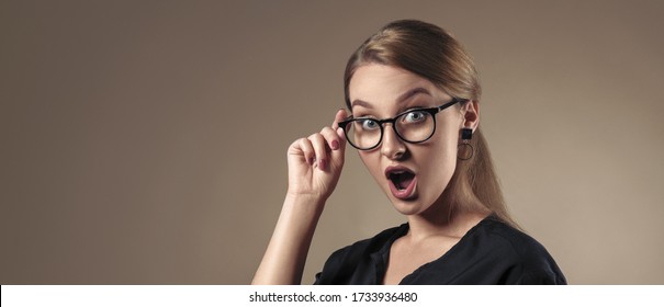 Portrait of surprised girl wearing eye glasses on beige background with copy space