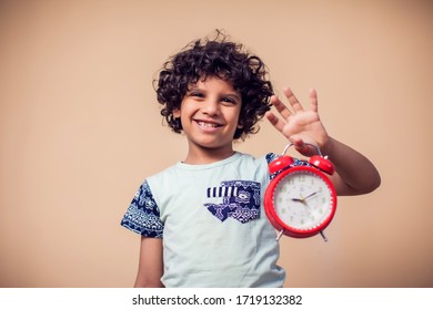 A Portrait Of Surprised Kid Boy Holding Alarm Clock. Children And Time Management Concept