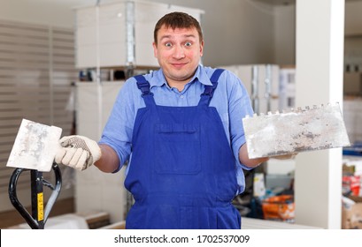 Portrait Of Surprised Male Builder Standing With Plastering Tools At Indoors Building Site
