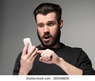 Portrait Of Surprised Man Talking On The Phone On A Gray Background