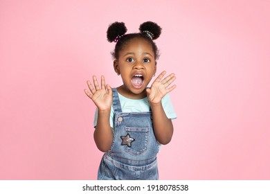 Portrait Of Surprised Screaming Cute Little African Girl Child Standing Isolated Over Pink Background, Looking At Camera With Open Mouth. Concept Of Children's Emotions, Facial Expression