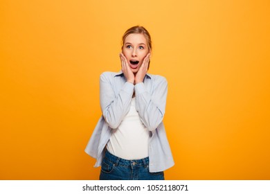 Portrait of a surprised young girl with braces looking at camera isolated over yellow background - Shutterstock ID 1052118071