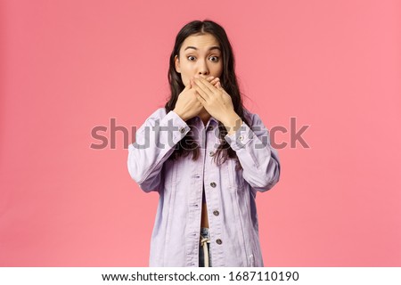 Portrait of surprised young girl found out something she shouldnt have, cover mouth as gasping and staring at camera speechless, trying not slip secret, gossiping, pink background