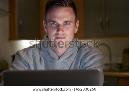 Portrait Of Suspicious Looking Man Using Laptop In Evening At Home