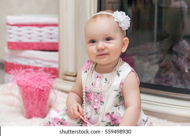 Portrait Of Sweet Baby Girl Wearing Floral Print Dress, Necklace And White Hair Bow Headband