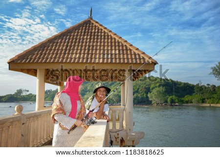 Portrait of a sweet couple wearing the traditional Malay fisherman costume at Tanjung Balau Fishing Jetty during sunrise . Love Concept.