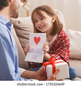 Portrait of sweet little girl greeting her dad with Father Day, presenting him gift box and creative card, home interior - Powered by Shutterstock