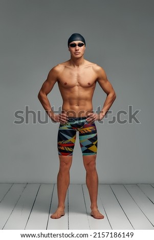 Portrait of a swimmer in a cap and mask, full-length portrait, young athlete swimmer wearing a cap and mask for swimming, copies of space, gray background