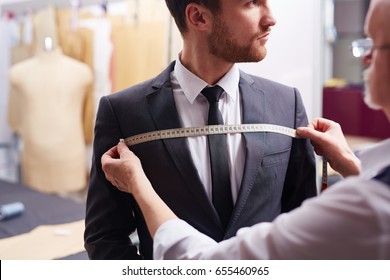 Portrait of tailor taking measurements of customer during model fitting