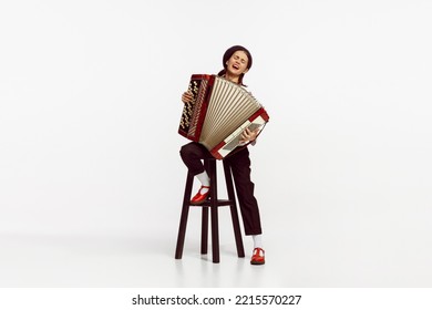 Portrait of talented beautiful woman playing accordion isolated over white studio background. Emotions. Concept of live music, performance, retro style, creativity, artistic lifestyle