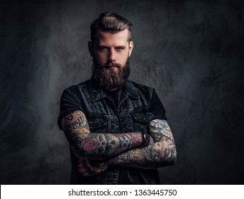 Portrait of a tattooed man with beard and hairstyle posing with his arms crossed. Studio photo against a dark wall - Powered by Shutterstock