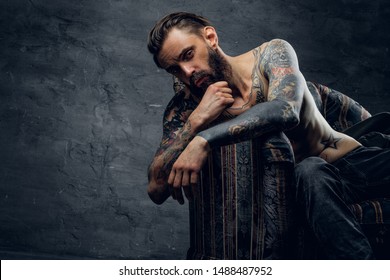 Portrait of tattooed sad man in despair, which is sitting on armchair at dark stash. - Shutterstock ID 1488487952