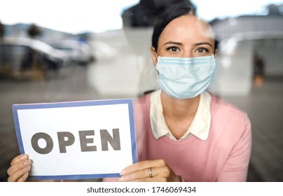 Portrait Of Teacher With Face Mask After Lockdown, Holding Open Sign.