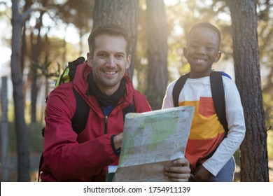 Portrait Of Teacher And Kid Reading Map In Forest