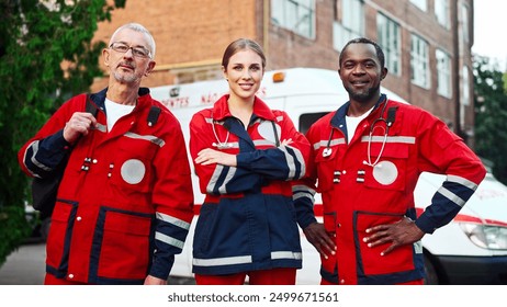 Portrait of team of paramedics in red medical uniform posing outdoors. Male and female doctors standing in street near ambulance and smiling at camera. Medical workers. Professional nurses, first aid - Powered by Shutterstock