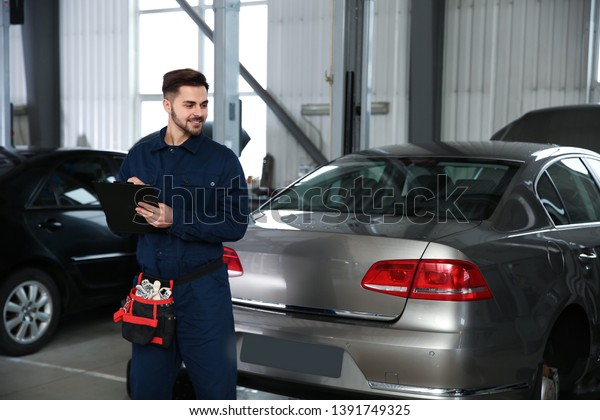 Portrait of technician with clipboard at automobile\
repair shop