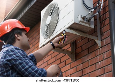 Portrait Of Technician In Hardhat Connecting Outdoor Air Conditioning Unit