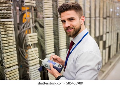 Portrait of technician using digital cable analyzer in server room