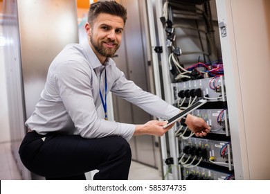 Portrait of technician using digital tablet while analyzing server in server room - Powered by Shutterstock