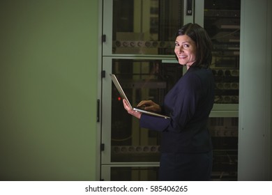 Portrait of technician using laptop while analyzing server in server room