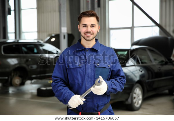 Portrait of technician with wrench at automobile\
repair shop