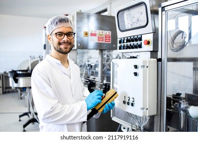 Portrait of technologist or worker in sterile white clothing standing by automated industrial machine in pharmaceutical company or factory. - Powered by Shutterstock