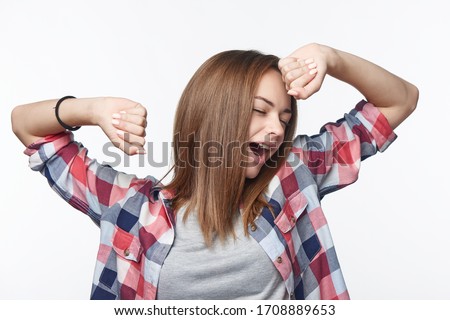 Portrait of teen casual girl waking yawning and stretching herself, studio shot on light background