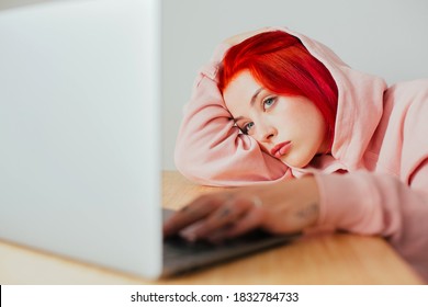 Portrait Of A Teen Girl Bored Lying On Desk Using In Laptop Computer To Surf Internet