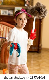 Portrait Of Teen Girl Cleaning Living Room With Cloth And Feather Brush