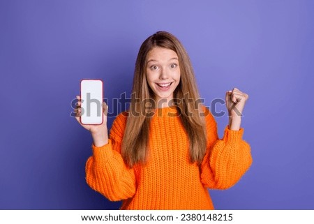 Portrait of teen girl raised fist up celebrating black friday discount code scanning hold smartphone isolated on purple color background