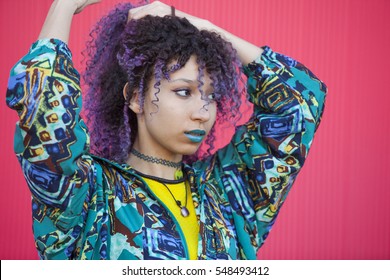 Portrait Of A Teen Woman With Purple Afro Hair And Blue Lips On A Pink Wall