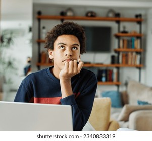 Portrait of teenage black boy using laptop computer and thinking and day dreaming looking through window at home. Teenage boy attending to online school class - Powered by Shutterstock