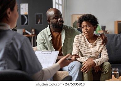 Portrait of teenage boy listening to psychologist during family therapy session with caring father copy space - Powered by Shutterstock