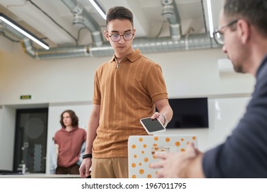 Portrait Of Teenage Boy Putting Smartphone In Box In No Gadget Classroom At School, Copy Space