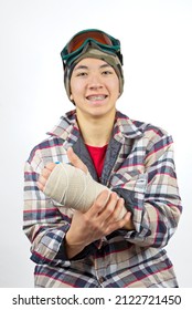 Portrait Of A Teenage Boy Showing His Broken Wrist All Bandaged Up After A Snowboarding Accident.