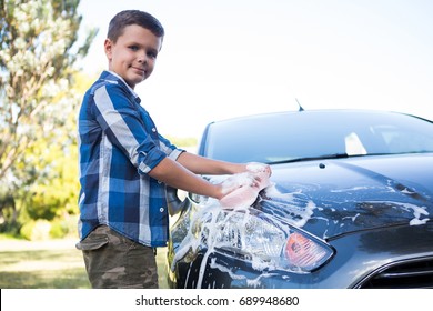 Portrait of teenage boy washing a car on a sunny day - Powered by Shutterstock